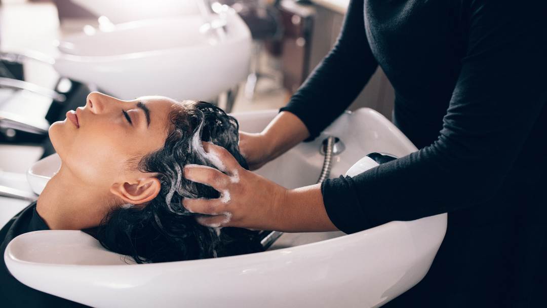 Žena u salonu, peru joj kosu uz djelotvorne sastojke