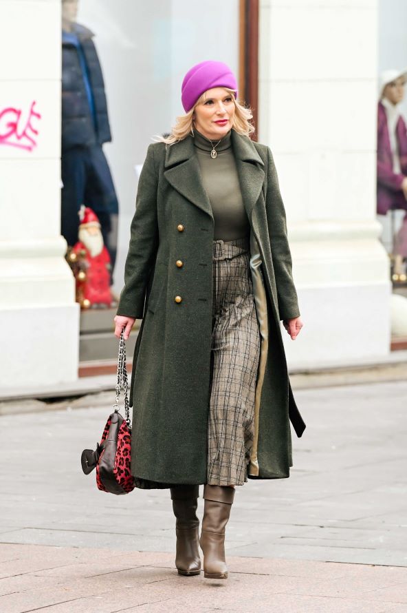 Plavuša na špici u maslinastom kaputu s upadljivim detaljima