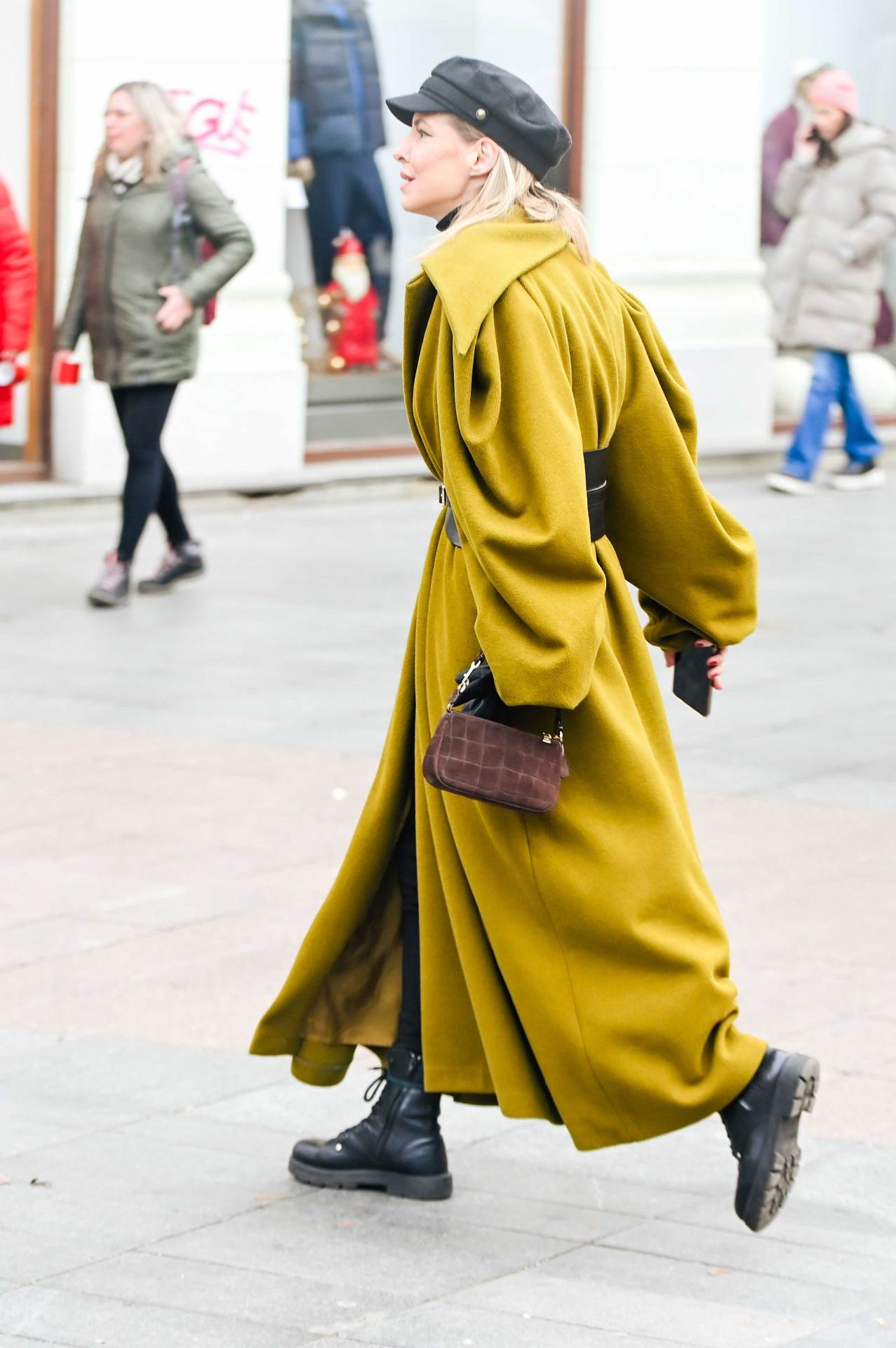 Plavuša na špici u maslinastom kaputu s upadljivim detaljima